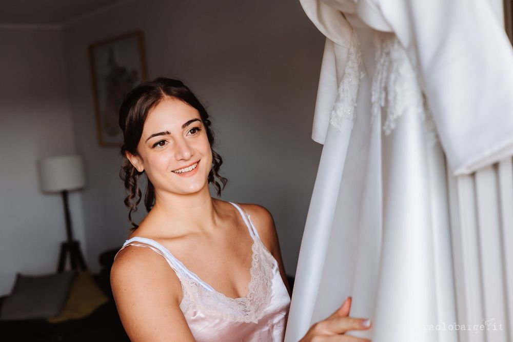 A joyful moment as someone admires a white wedding dress hanging nearby.