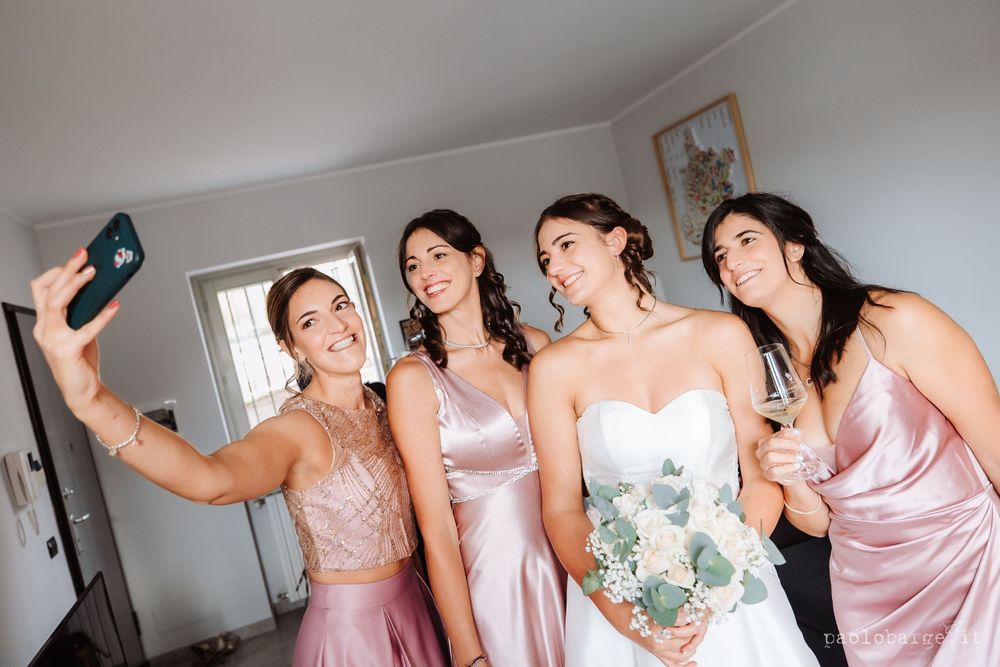 Wedding party in pink dresses takes cheerful selfies during pre-wedding preparations.