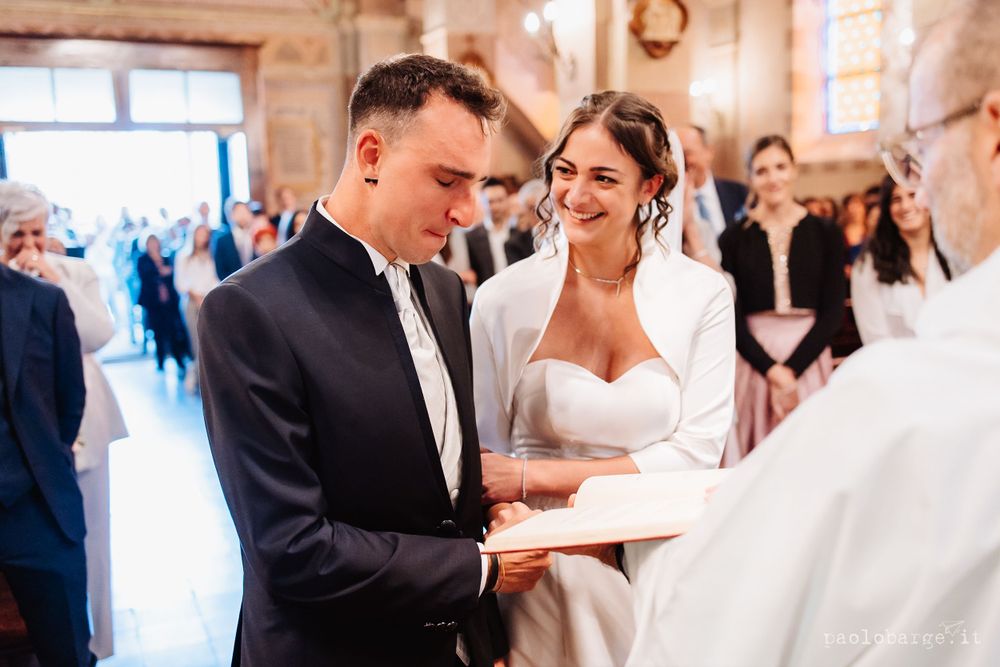 Couple participates in traditional wedding ceremony inside ornate church setting.