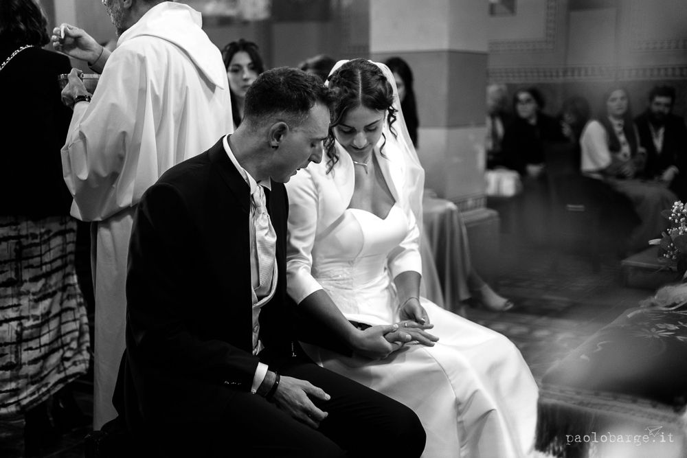 A traditional black and white wedding ceremony scene inside a dimly lit church.