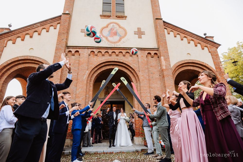 Guests toss confetti outside a beautiful brick church with arched doorways.