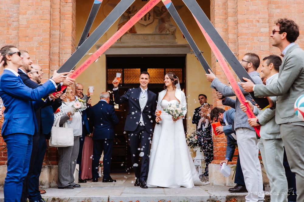 Wedding party using confetti cannons to celebrate outside church steps.