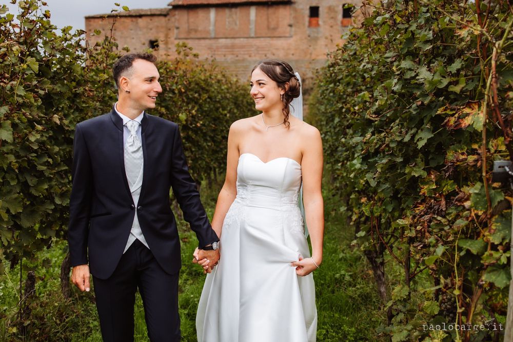 Newlyweds share a joyful moment among vineyard rows in Italy.