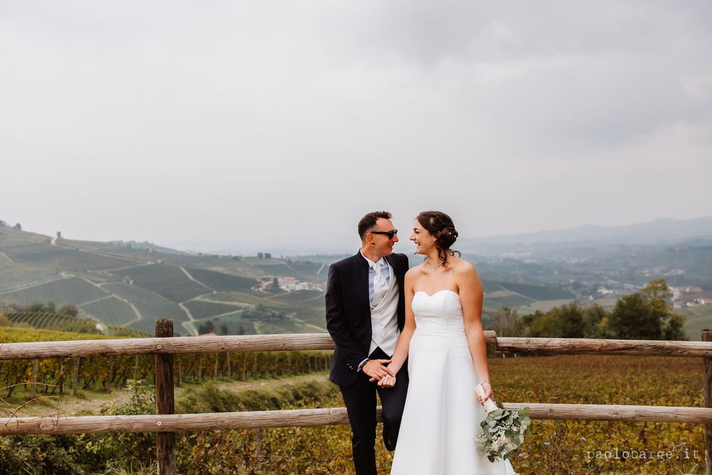 Wedding couple enjoys scenic Italian hillside vineyard views.