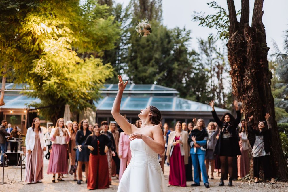 Wedding celebration with guests watching in colorful dresses under autumn trees.