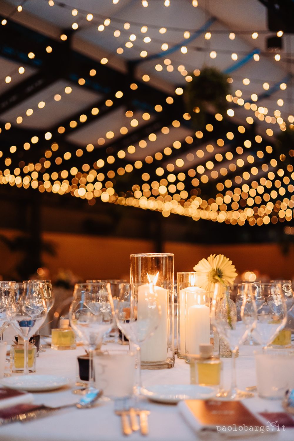 Romantic string lights create a starry effect above elegant wedding reception tables.