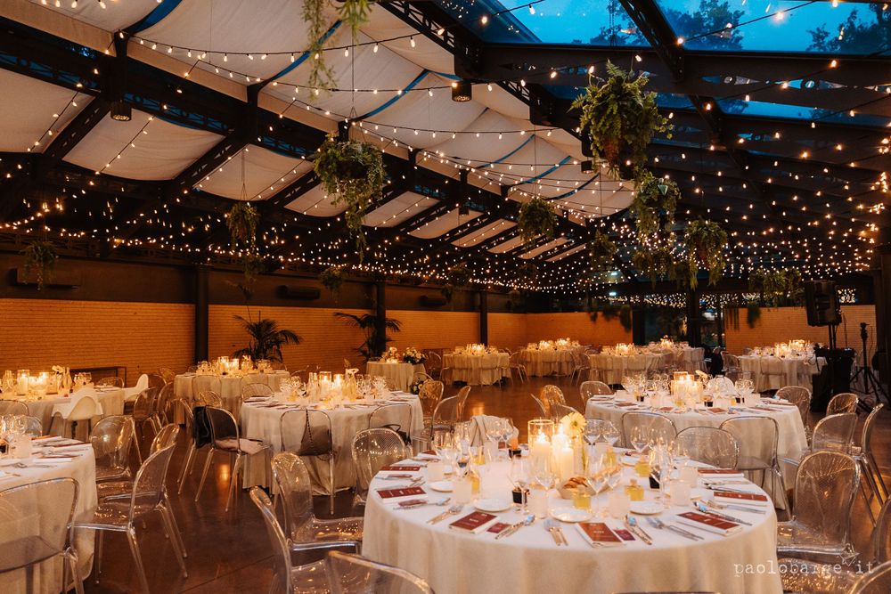 Wedding reception hall decorated with twinkling string lights and round tables.