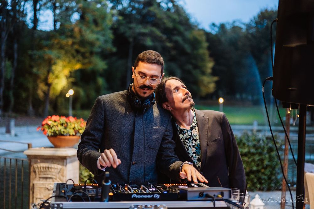 DJ duo performs at outdoor evening wedding reception.