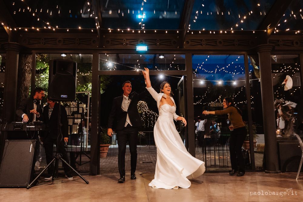 A joyful dance celebration under twinkling lights at an indoor wedding reception venue.
