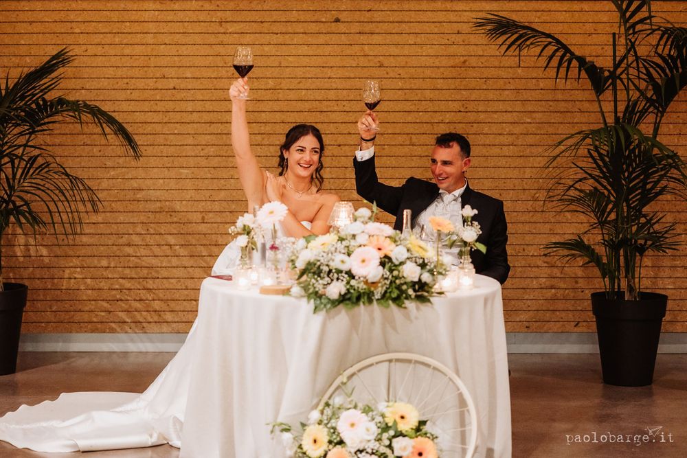 Newlyweds raise their glasses in celebration at their wedding reception head table.