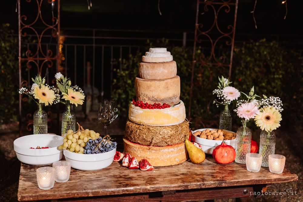 Rustic wedding dessert table featuring a tiered cake with fresh fruits and floral decorations.