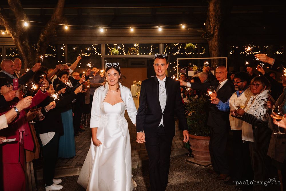 Wedding exit with sparklers lighting up the night as couple walks through crowd.