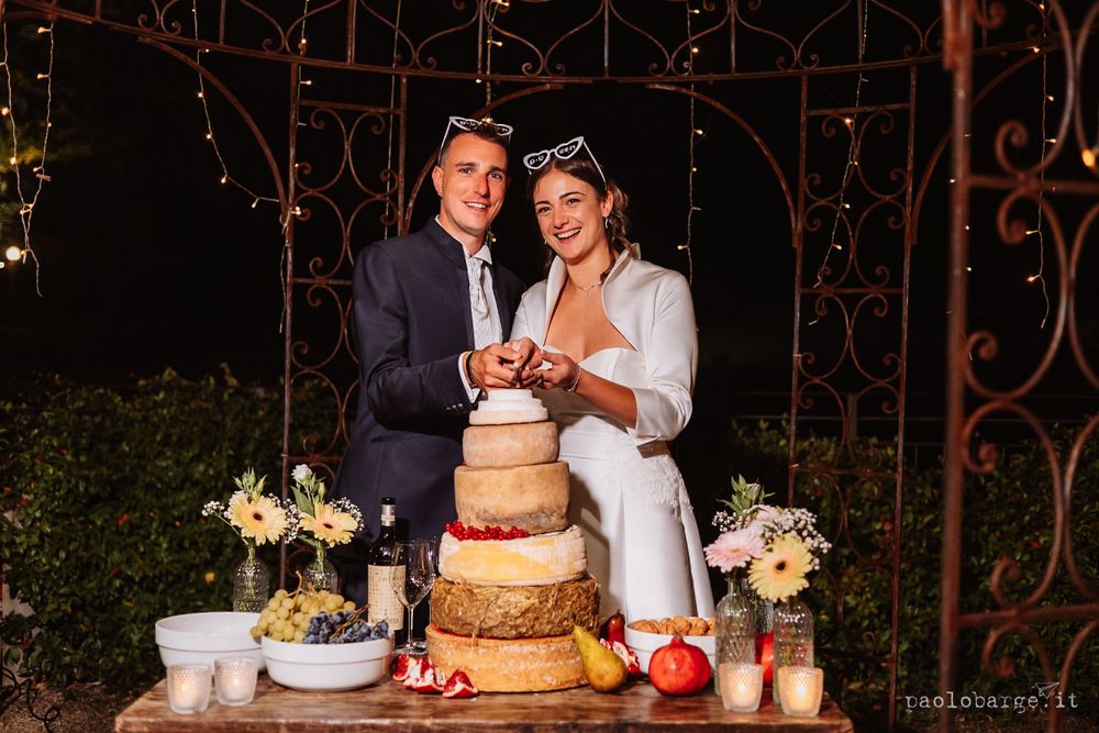 Elegant tiered wedding cake with rustic decorations on display at evening reception.