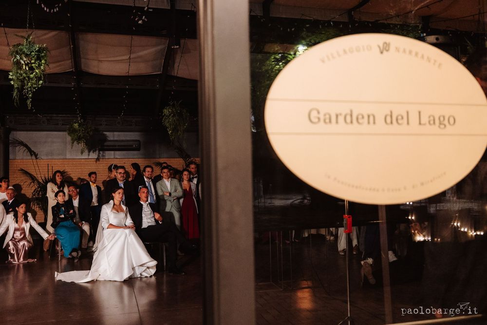 Wedding venue sign for Garden del Lago with reception celebration in background.