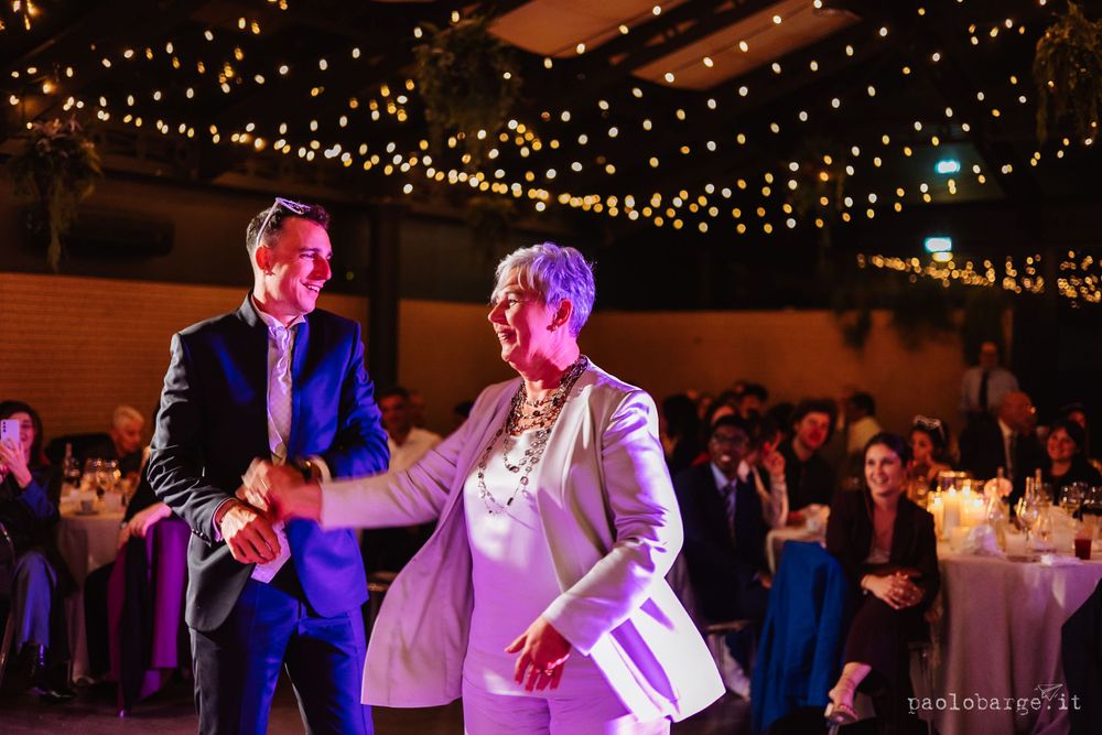 Dance floor moment illuminated by twinkle lights and colored lighting at wedding reception.