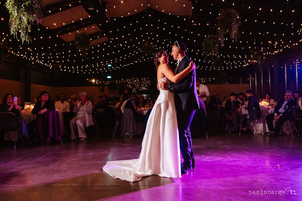 First dance at wedding reception under twinkling lights and purple ambiance.