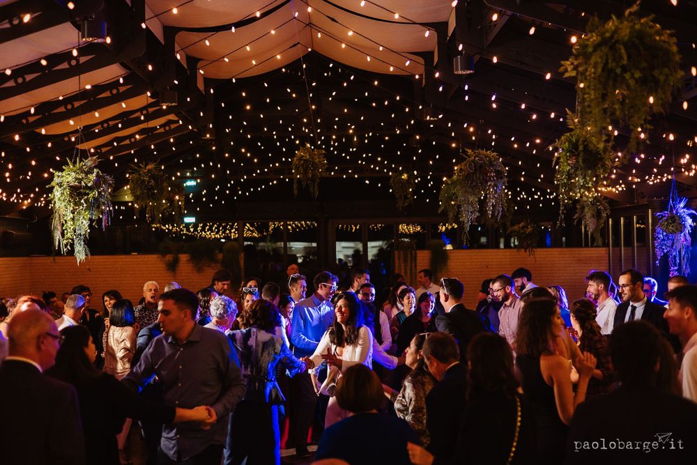 Wedding reception dance floor filled with guests under twinkling string lights and romantic mood lighting.