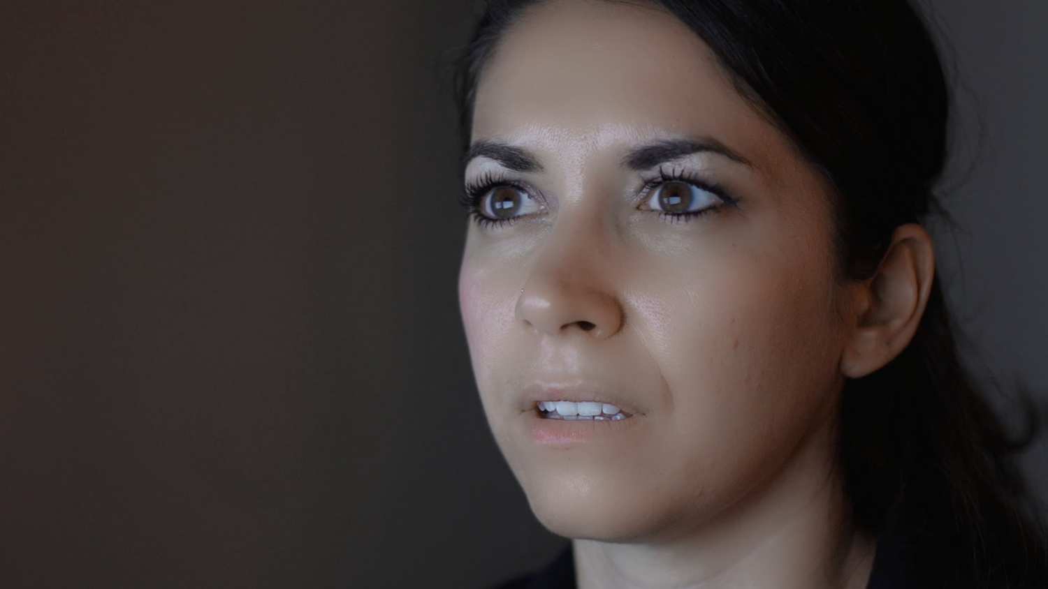 A close-up portrait shot showing dramatic lighting against a dark background.