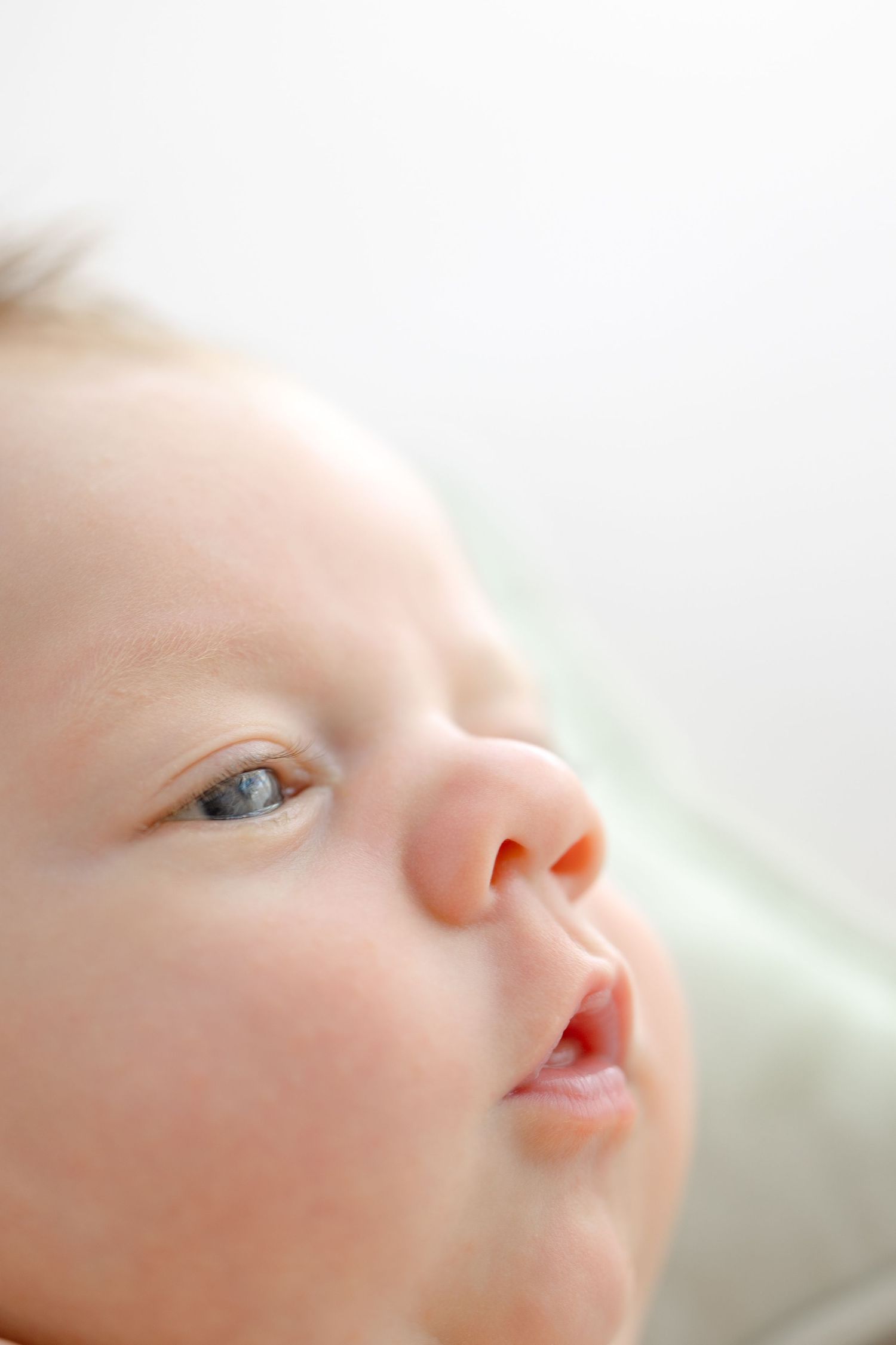 Close up profile view of an infant's face with soft lighting highlighting their delicate features and clear eyes.