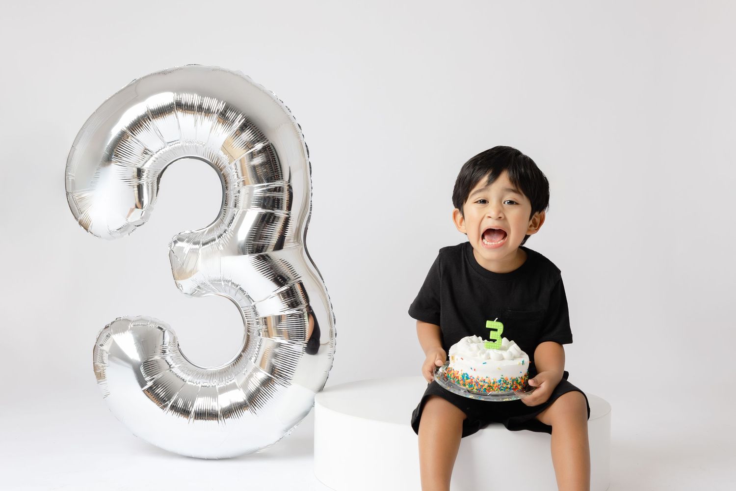 A series of milestone photos showing a child growing up with silver number balloons marking each age.