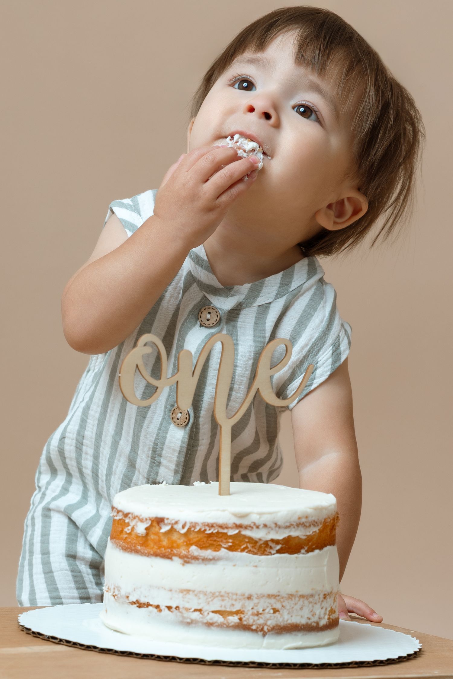 Sequence of photos showing a toddler in striped outfit enjoying and making a mess while eating birthday cake.