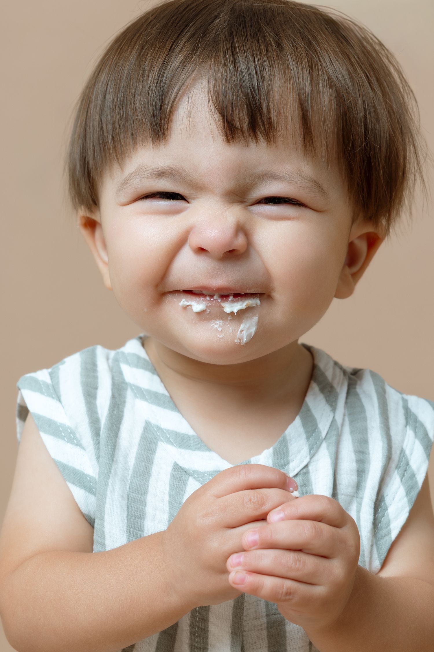 Series of photos showing a toddler in striped shirt getting messy while eating yogurt or ice cream.