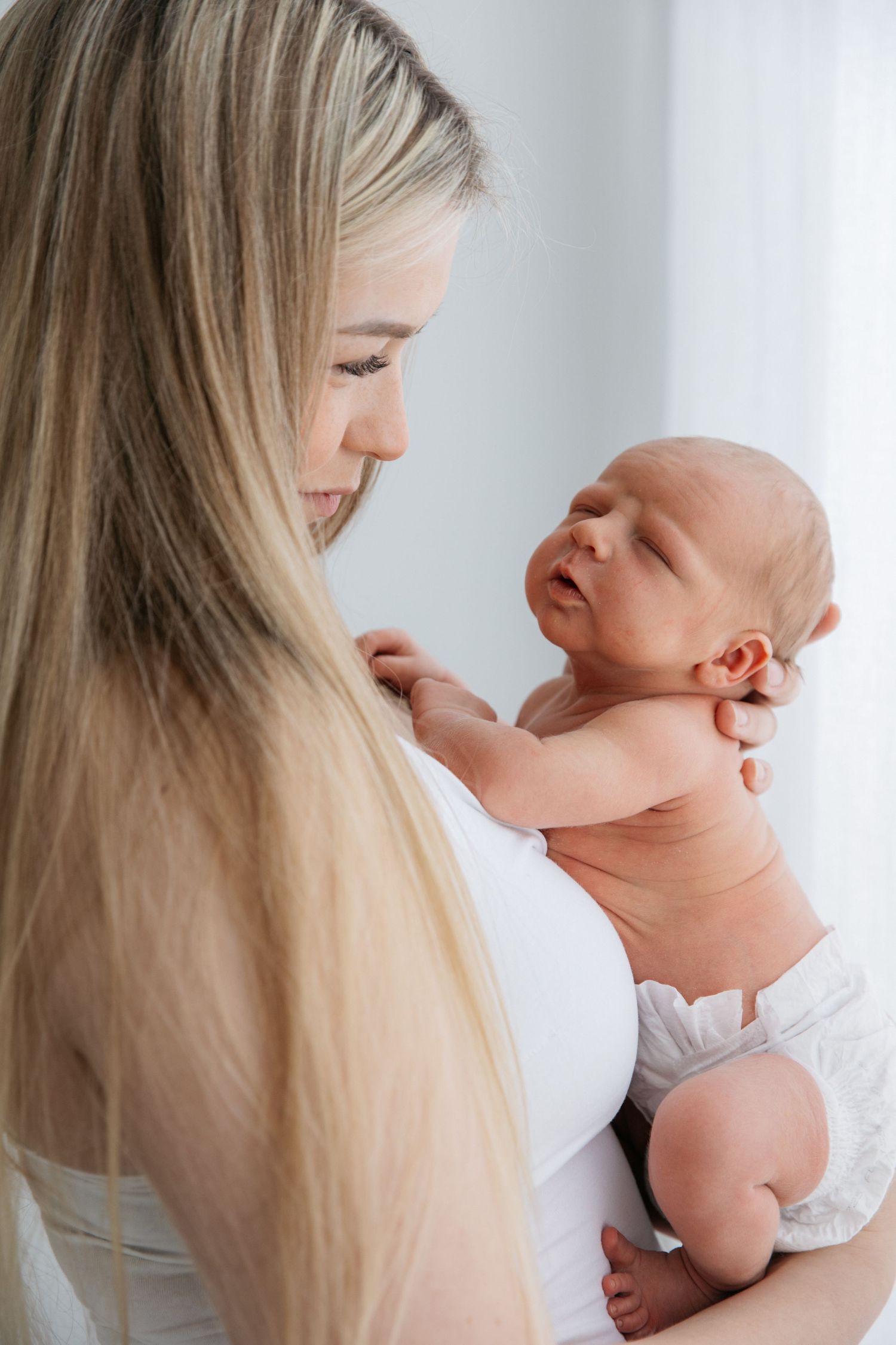 Tender moment between mother and newborn baby in white.
