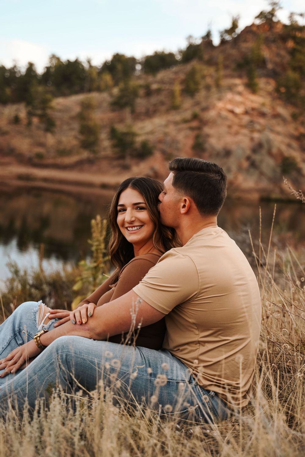 Couple sitting together on hillside overlooking scenic mountain lake.