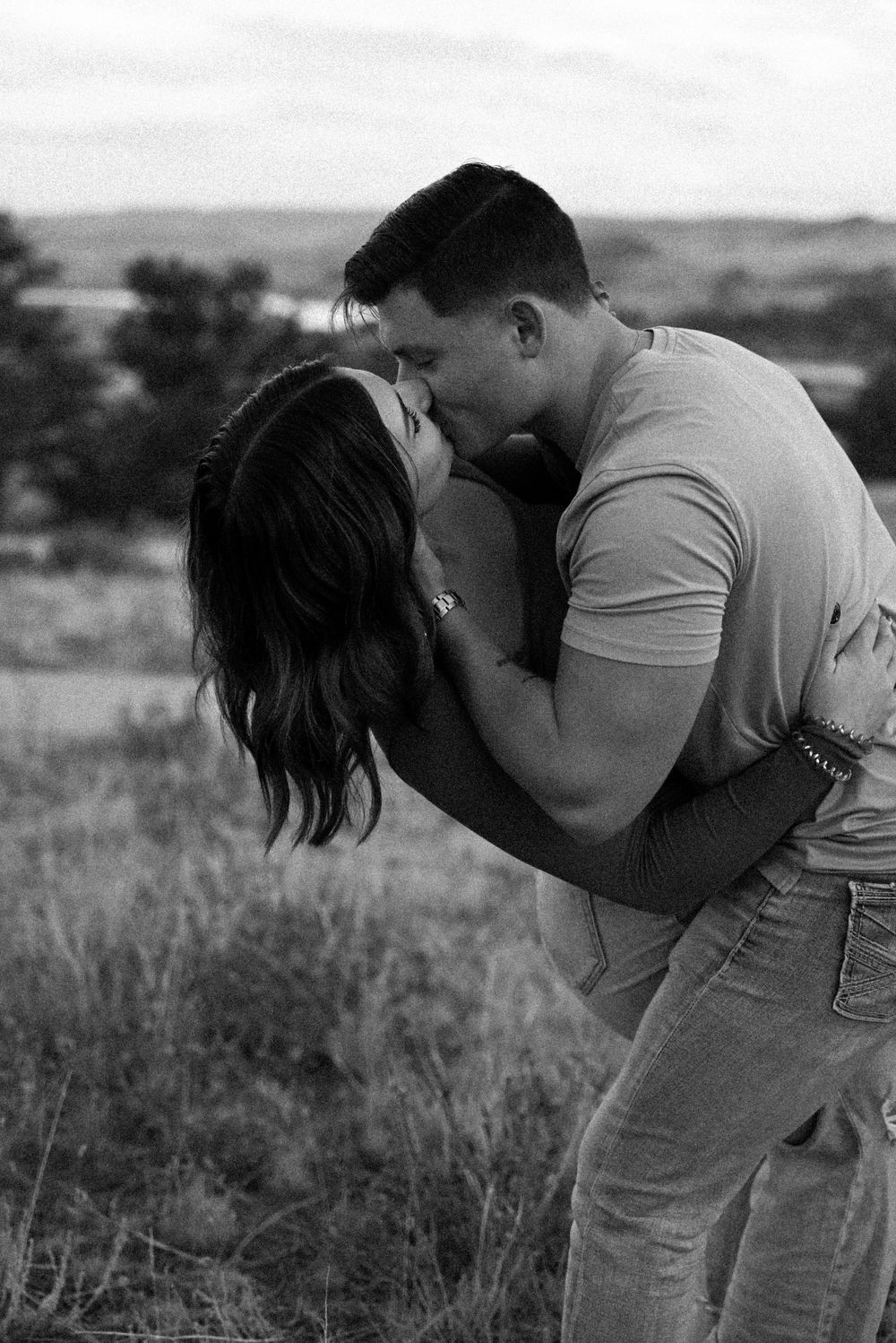 Black and white romantic portrait of couple embracing in mountain setting.