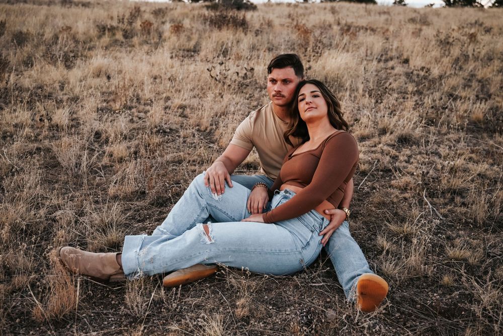 Casual couple in denim relaxing together in autumn field at sunset.