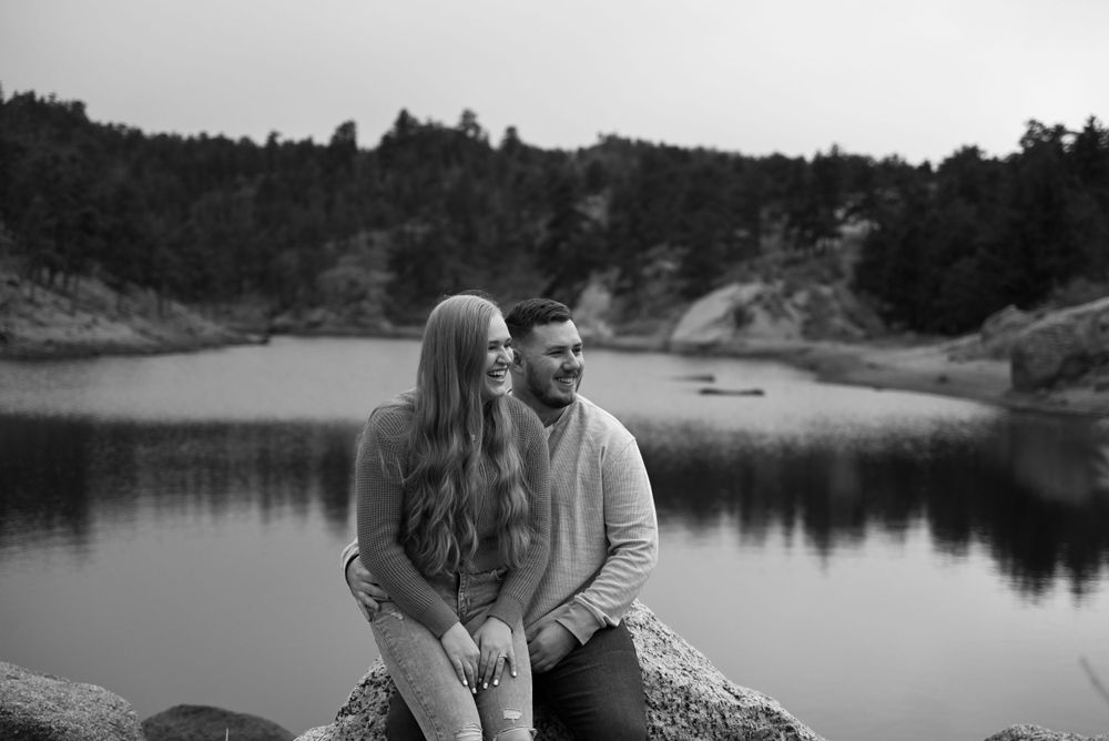 Black and white lakeside engagement photos with mountain views and reflective water.
