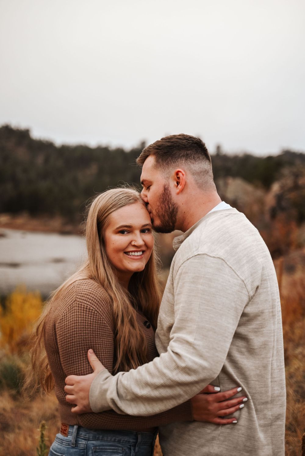 Cozy fall engagement session with couples wearing neutral sweaters against moody skies.