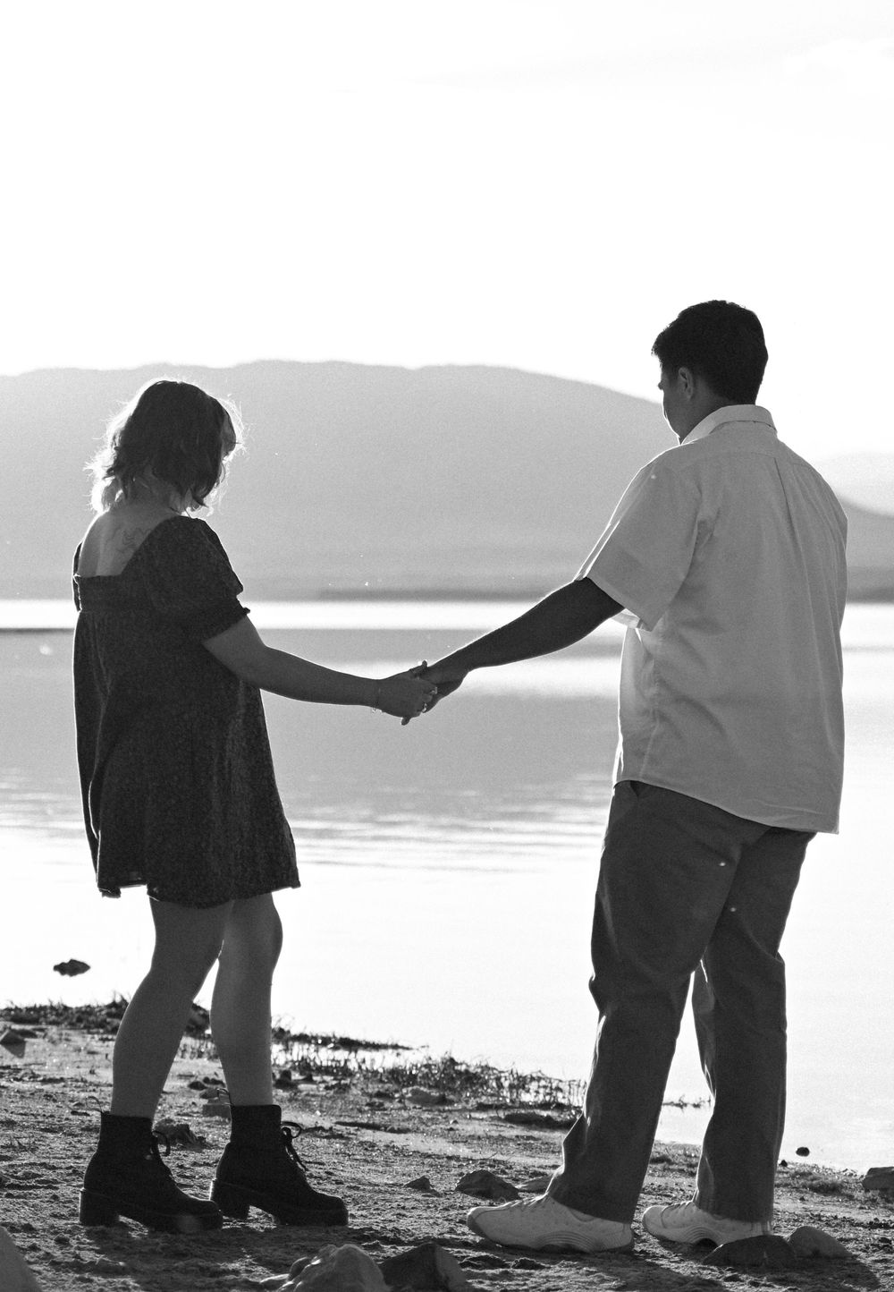 Black and white silhouettes playing and interacting on a beach shoreline.