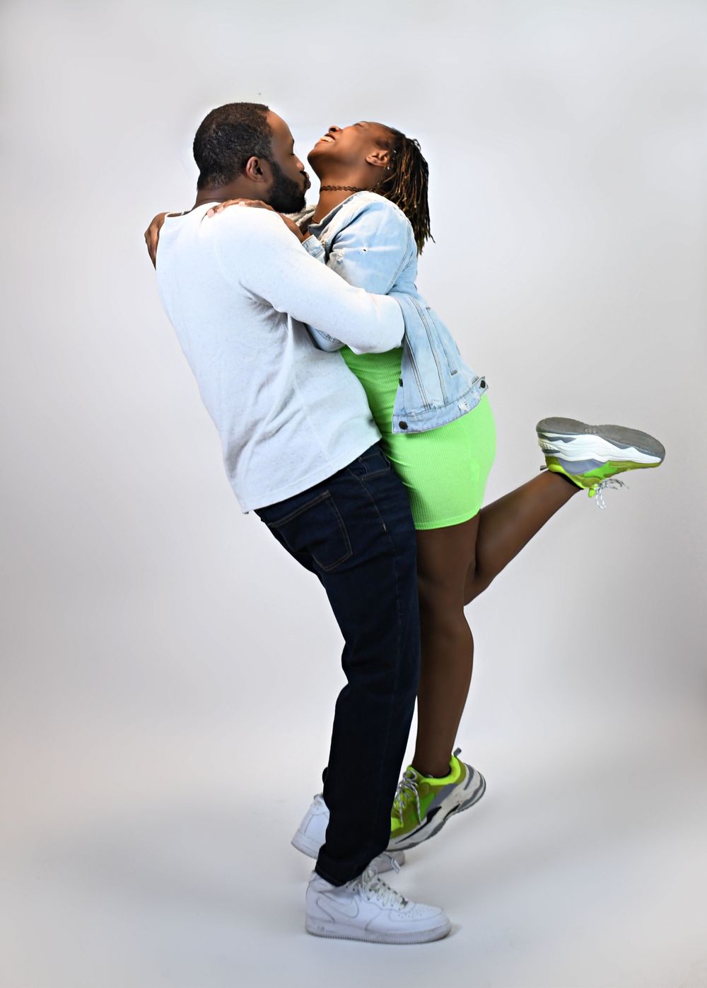 A couple sharing an intimate embrace and laughing together against a white background.