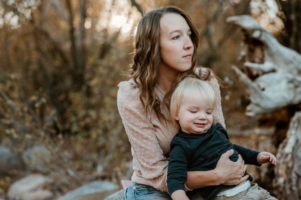 A tender family moment captured by a stream during golden hour.