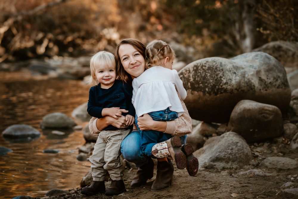 Group sitting together on rocky riverbank during golden hour.