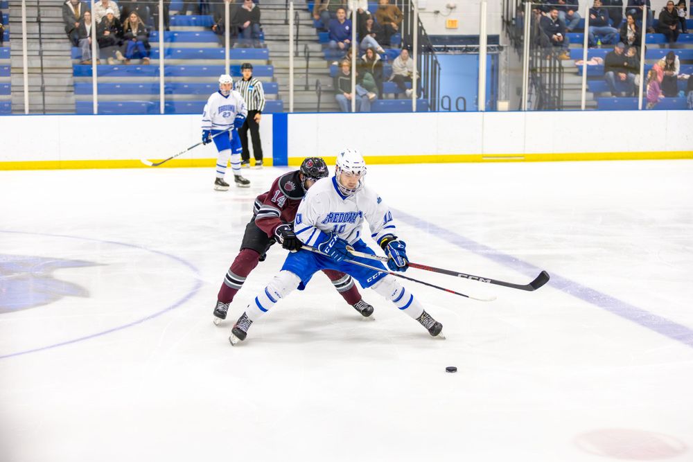 Hockey players compete for the puck during an intense ice hockey match on the rink.
