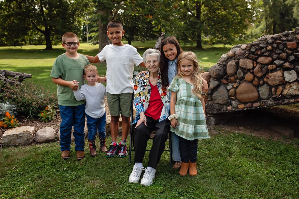 Children standing together by a stone wall in a garden setting.