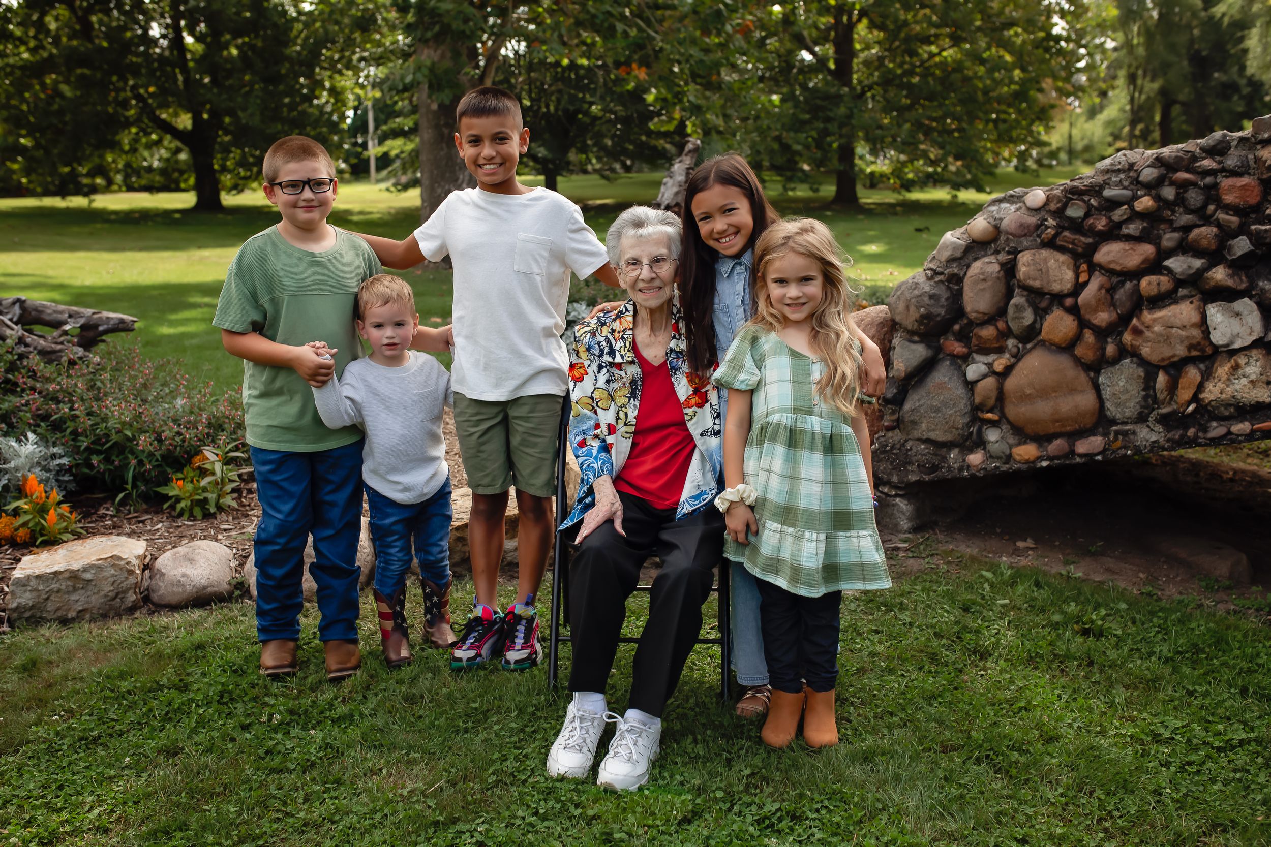 Children standing together by a stone wall in a garden setting.