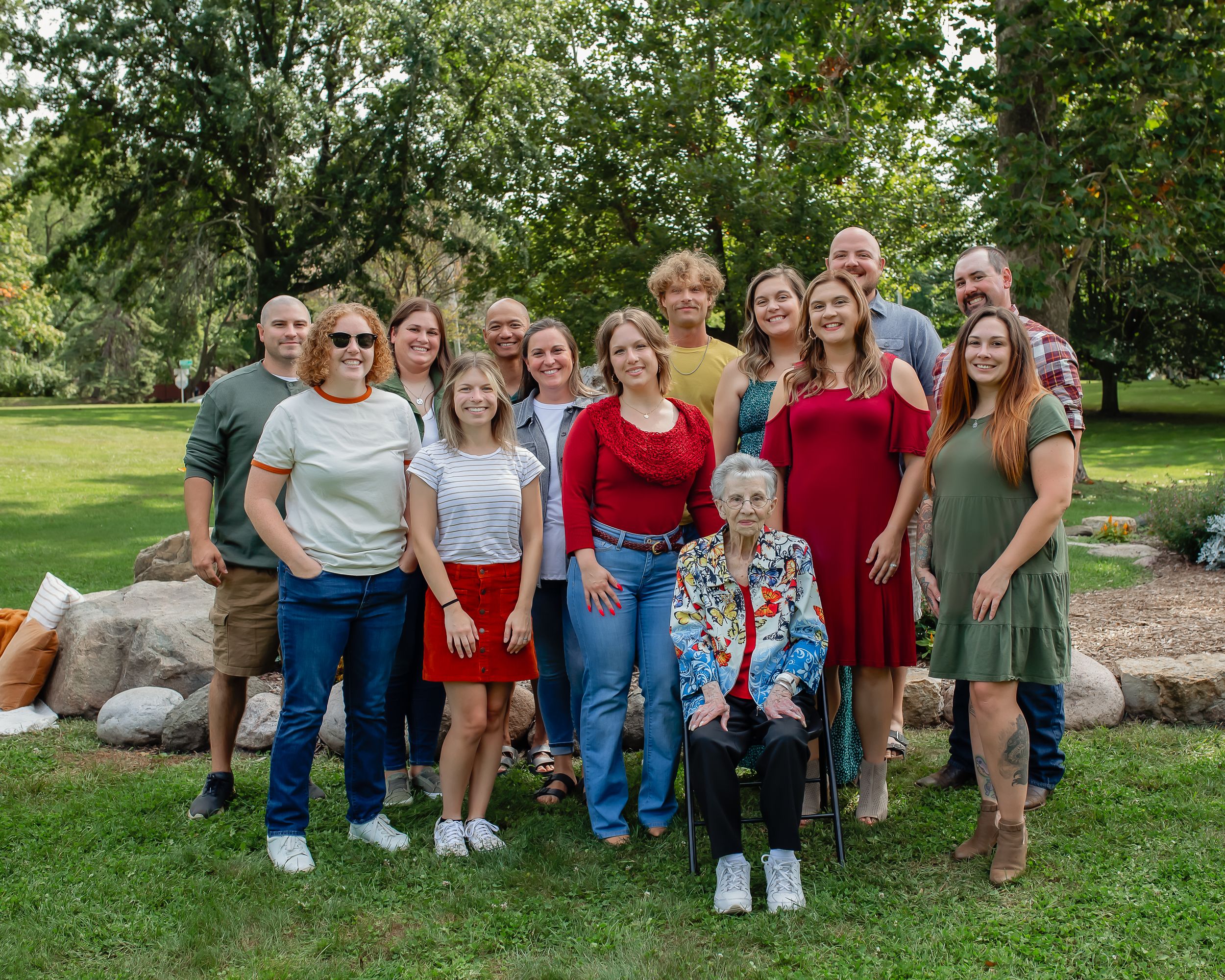 Family gathering outdoors with casual and dressy attire against natural garden backdrop.