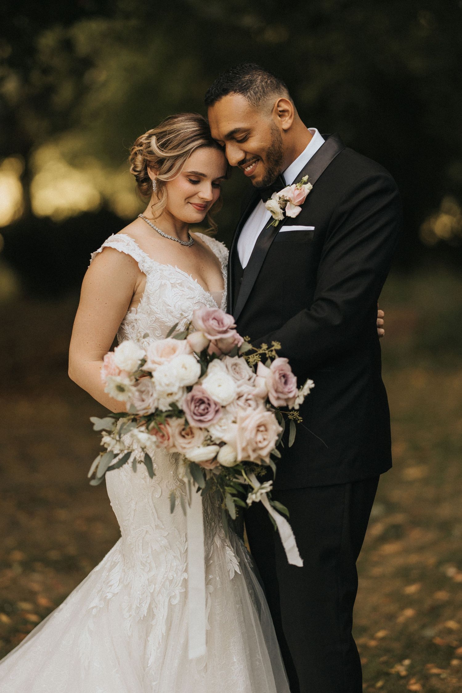 Romantic wedding couple shares intimate moment outdoors while bride holds beautiful bouquet - taken by Grimsby photographers.
