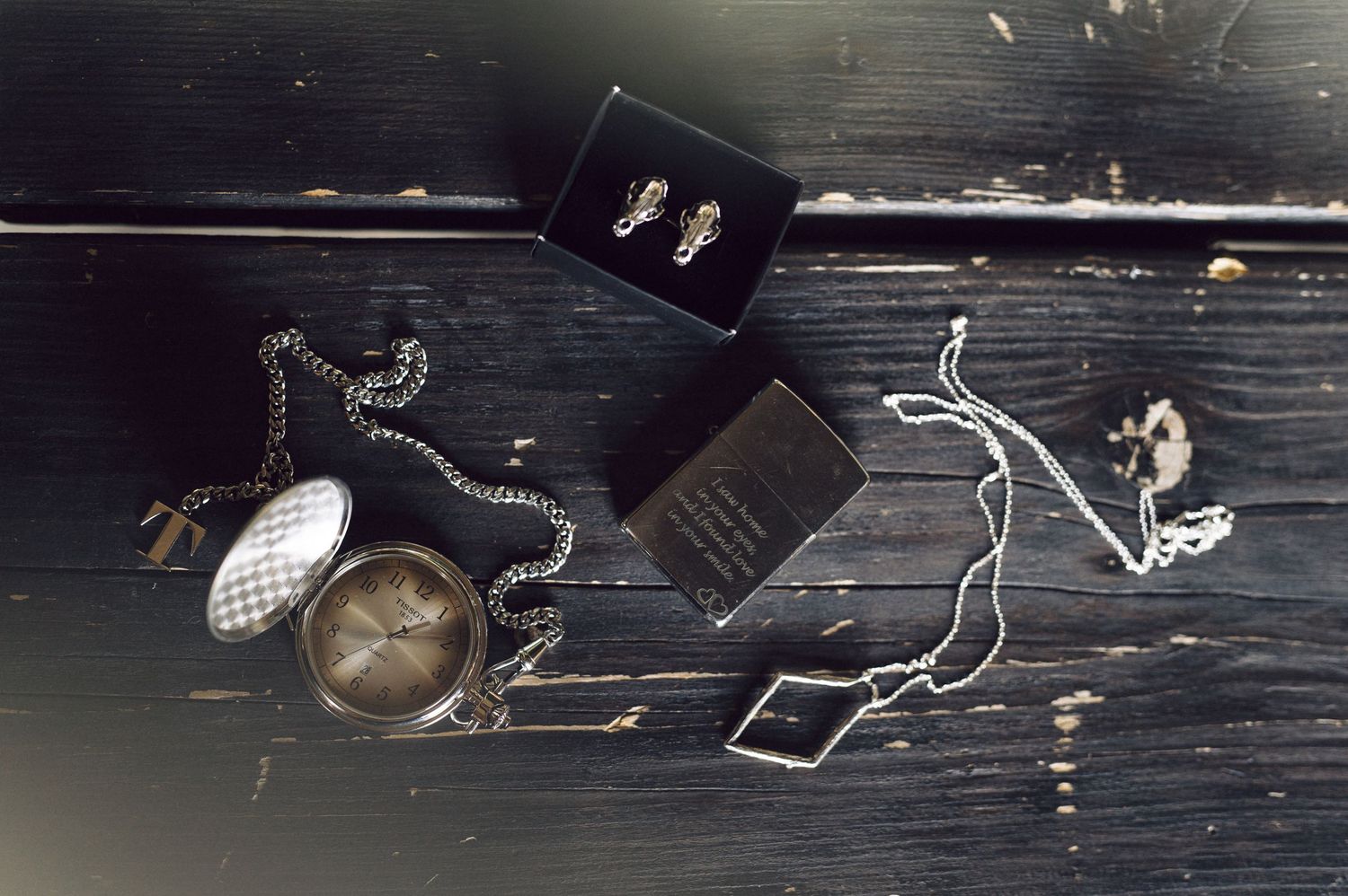 Vintage pocket watch and jewelry accessories arranged on dark wooden surface.