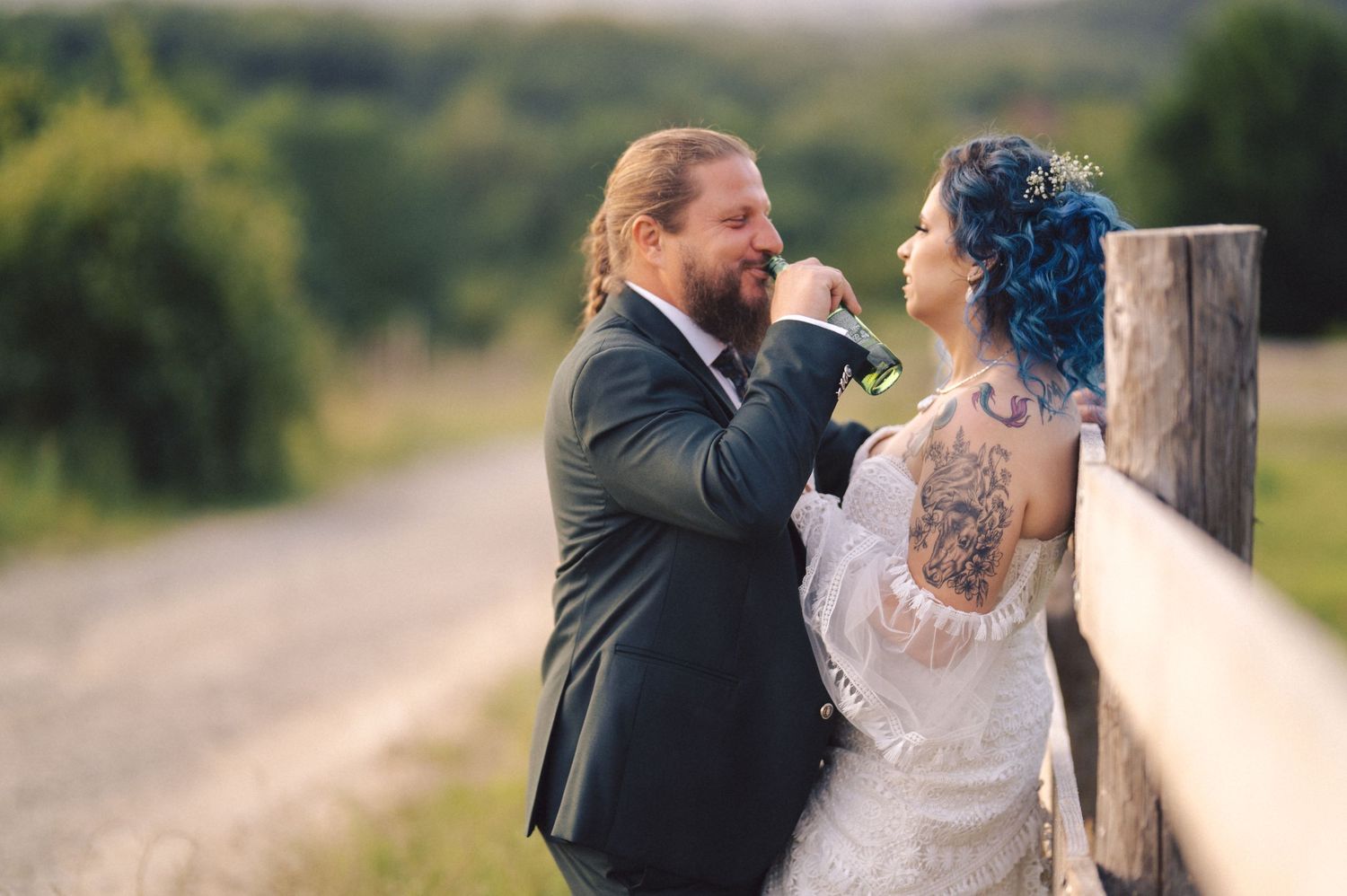 A wedding couple shares an intimate embrace outdoors against a scenic natural backdrop during golden hour.