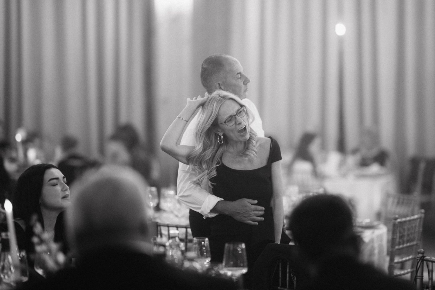 Wedding guests dance together on the dance floor while enjoying a lively celebration at a reception.