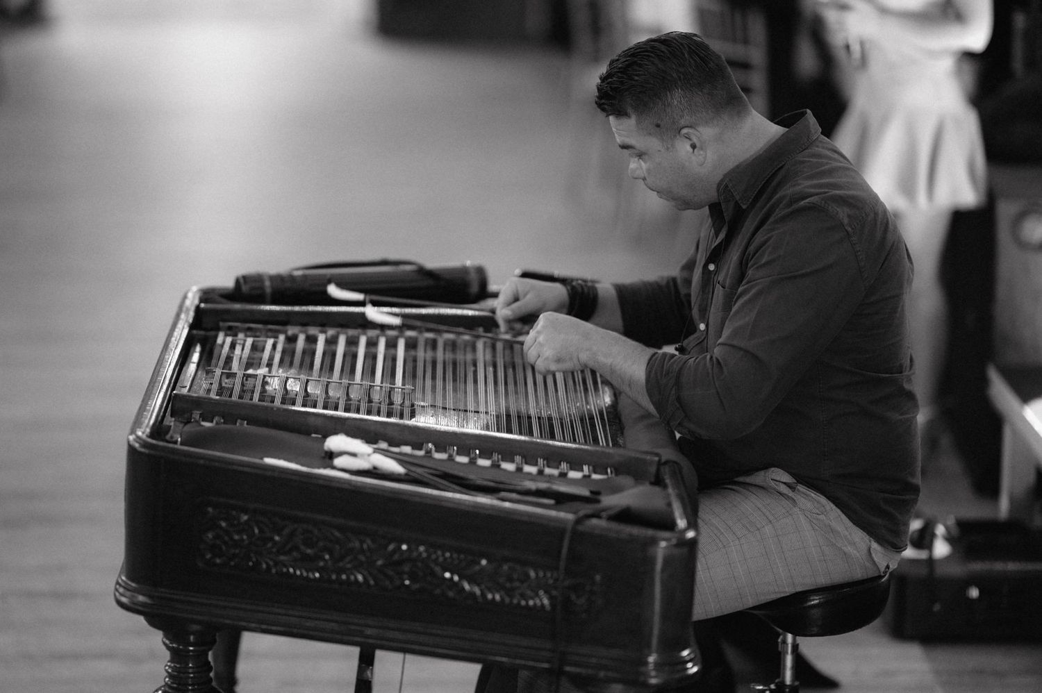 Vintage black and white photograph of a person playing an accordian while seated on a bench.