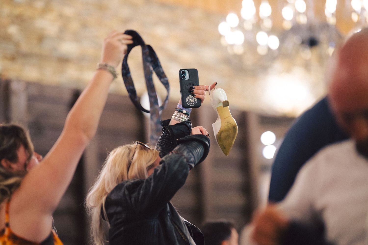 Concert attendees hold up phones and cameras to capture a special moment during a performance in an ornate venue.