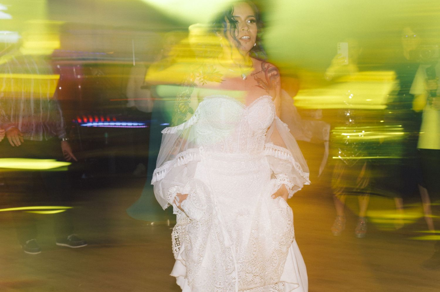 Long exposure photograph of someone in a white wedding dress dancing with light trails creating a dreamy motion blur effect.