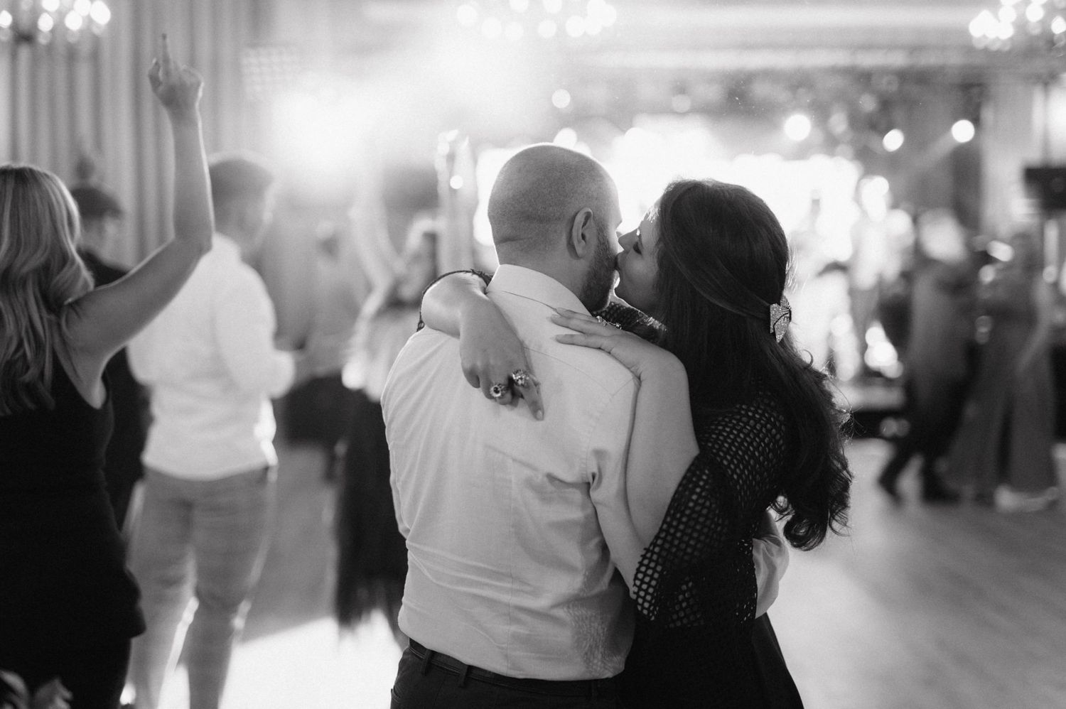 A black and white photo showing a row of people dancing at an event, arms in motion.