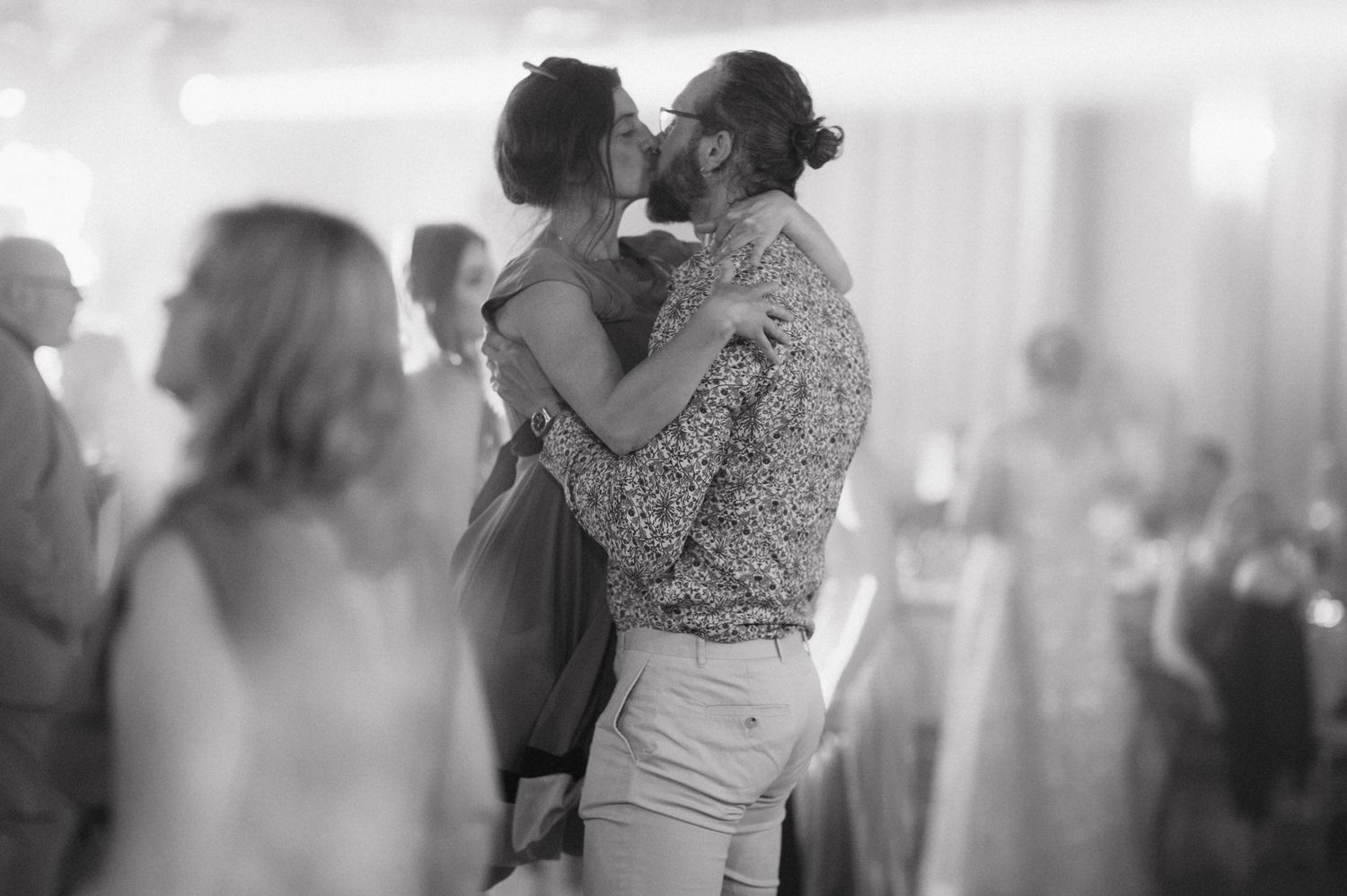 A couple dances close together during a romantic slow dance at a dimly lit event.
