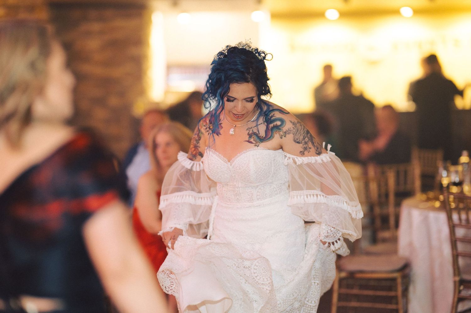 A joyful scene at a wedding reception as someone in a white wedding dress dances with vibrant energy on the dance floor.